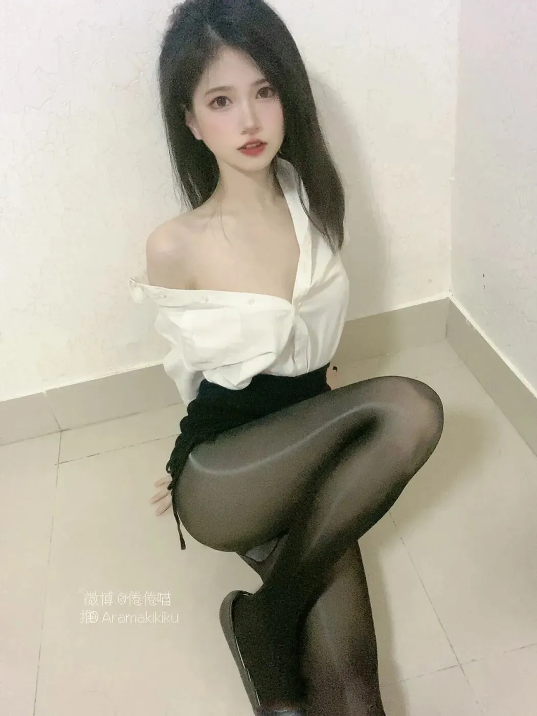 倦倦喵白衬衫搭配黑色短裙与黑丝袜，在简洁墙角以低机位呈现通勤氛围