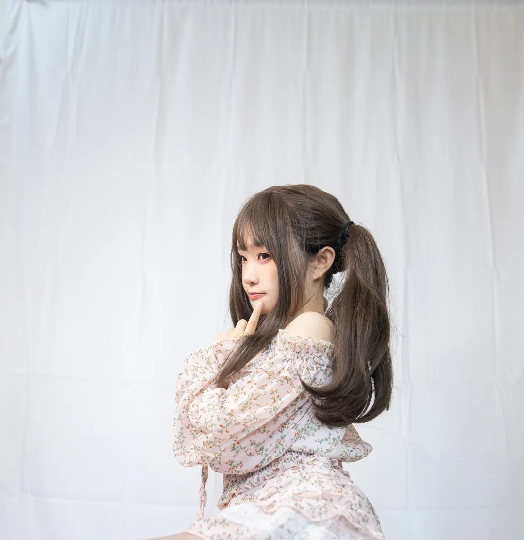 神沢永莉碎花露肩裙棚拍侧颜回眸,棕色马尾顺肩滑落,白色垂帘背景营造梦幻少女气质