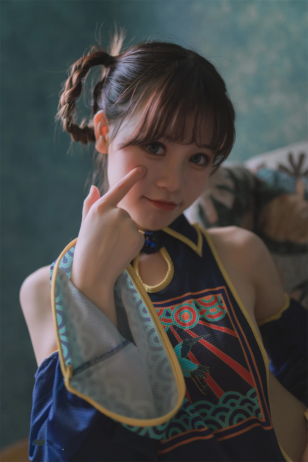 星黛鹿鹿在近景里穿蓝黑露肩角色装指着脸侧的照片
