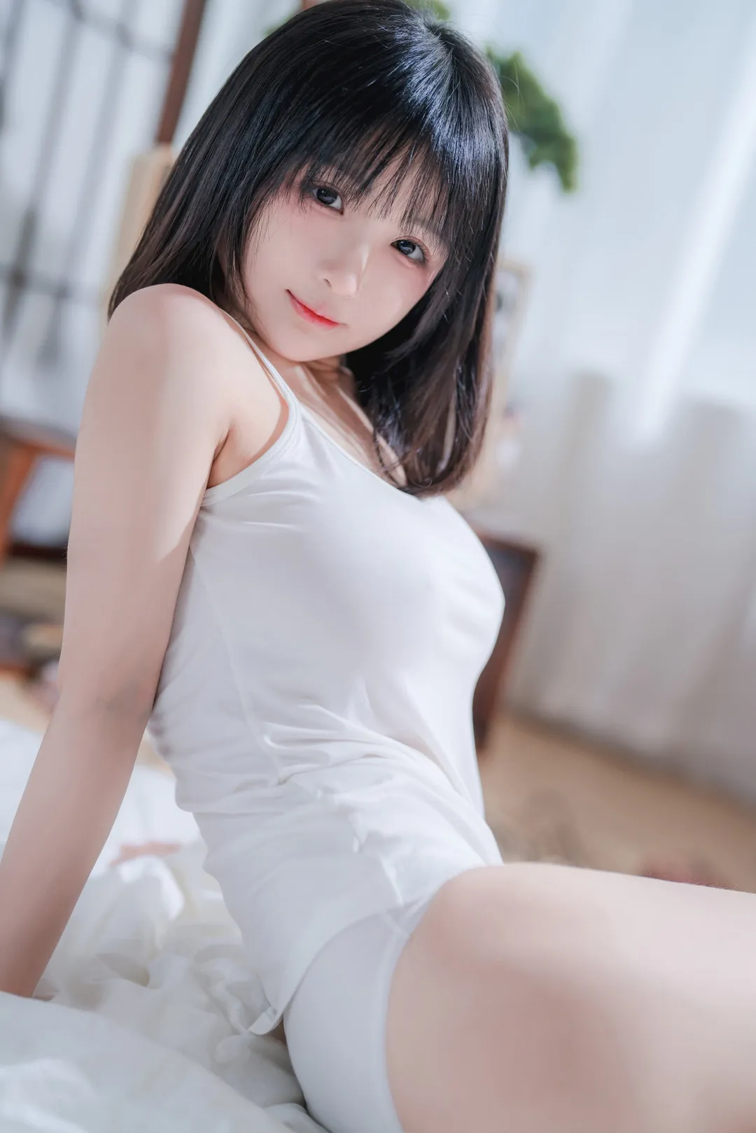 桜井宁宁在床边穿白色无袖短裙近景出镜的照片