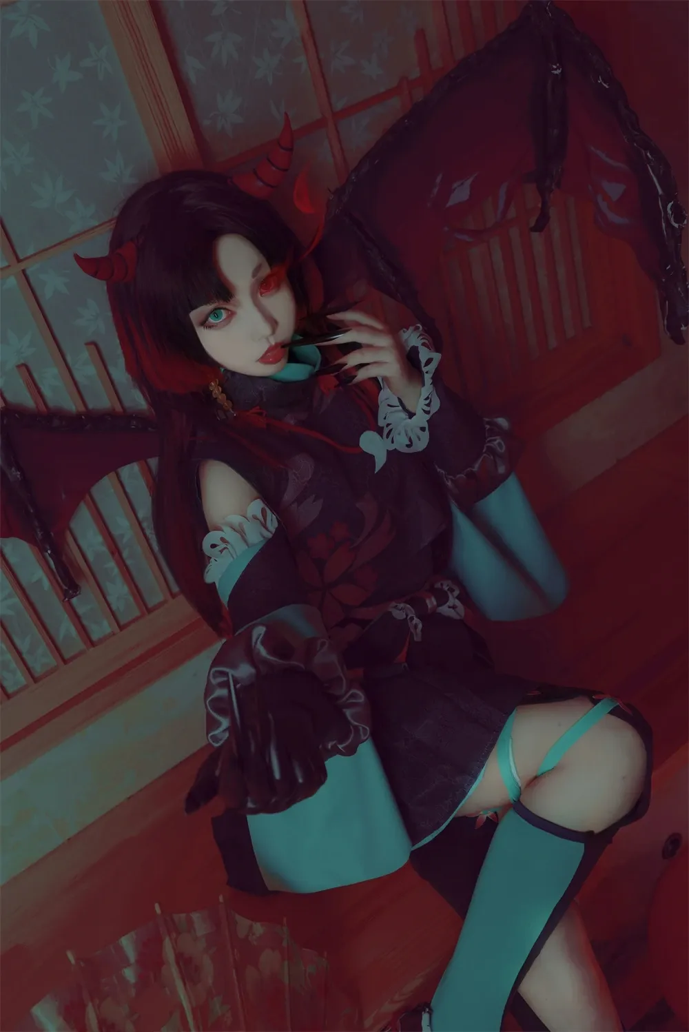 白易子教主穿红色角色服在暗色灯光中坐姿出镜的写真