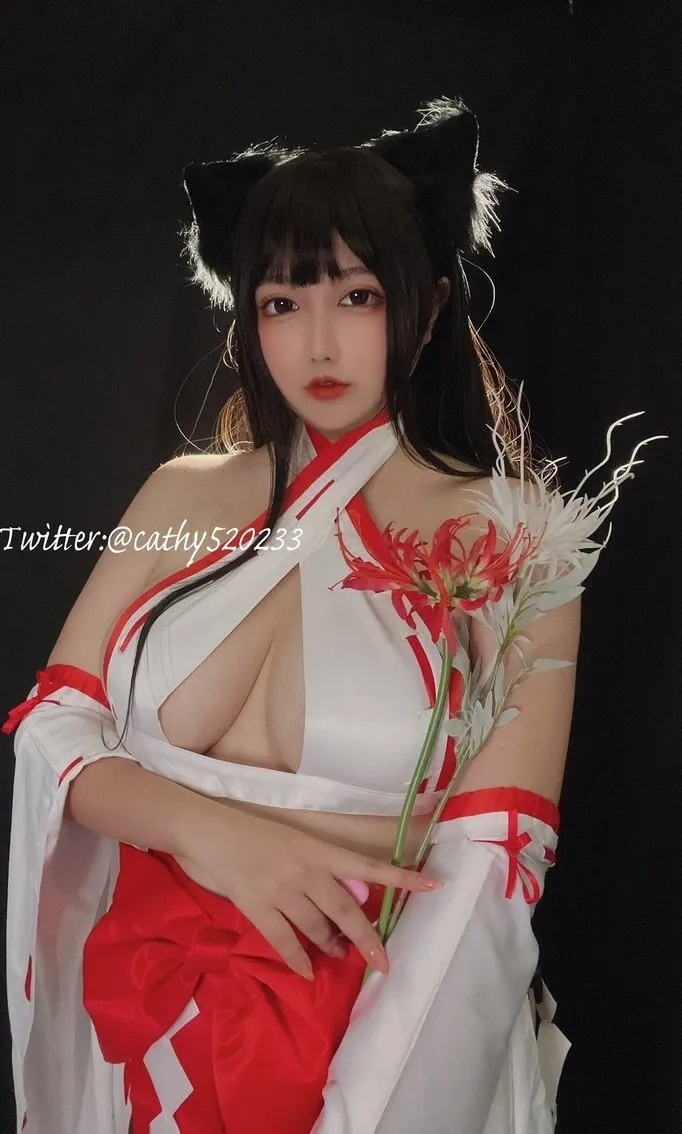 椒妮佐仁在黑色背景前站姿持花出镜，黑色长发猫耳头饰配红白露肩服装