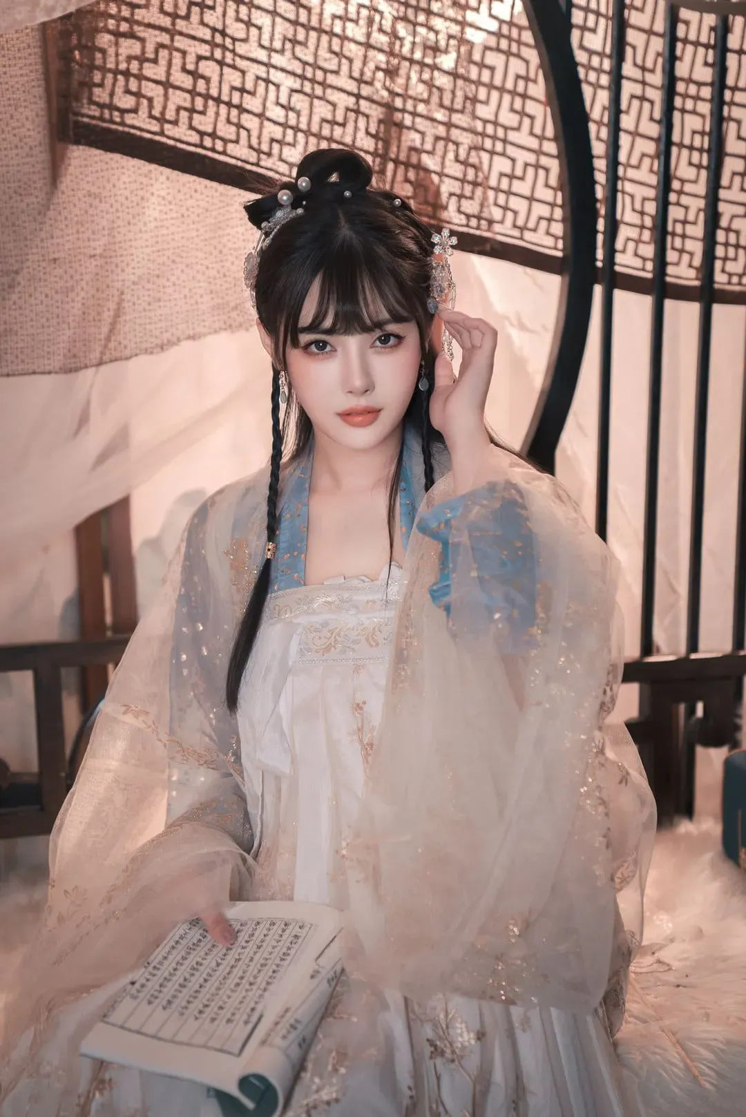 恋恋艾妮坐在屏风与纱帐前,穿浅色汉服手拿书卷的正面人物造型