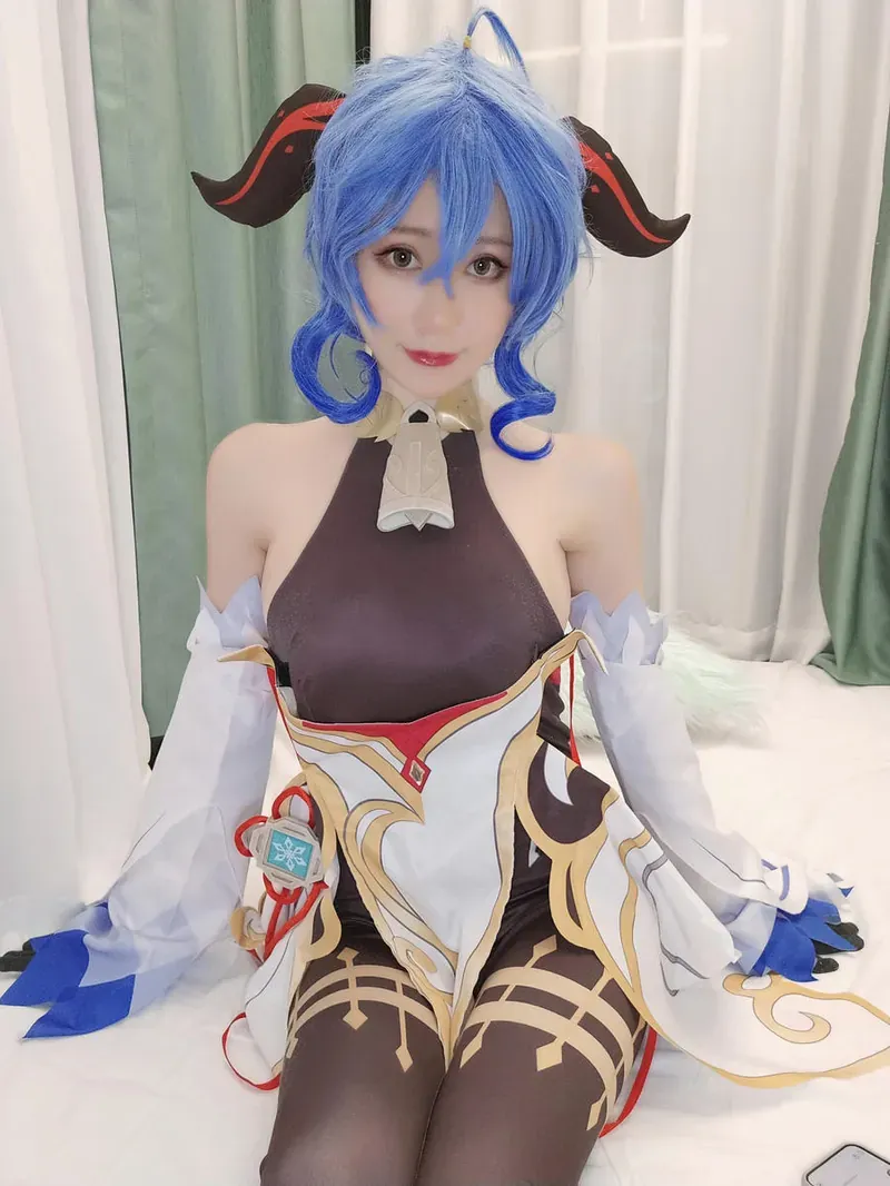 钛合金titi穿蓝白角色服坐在白色床上的照片