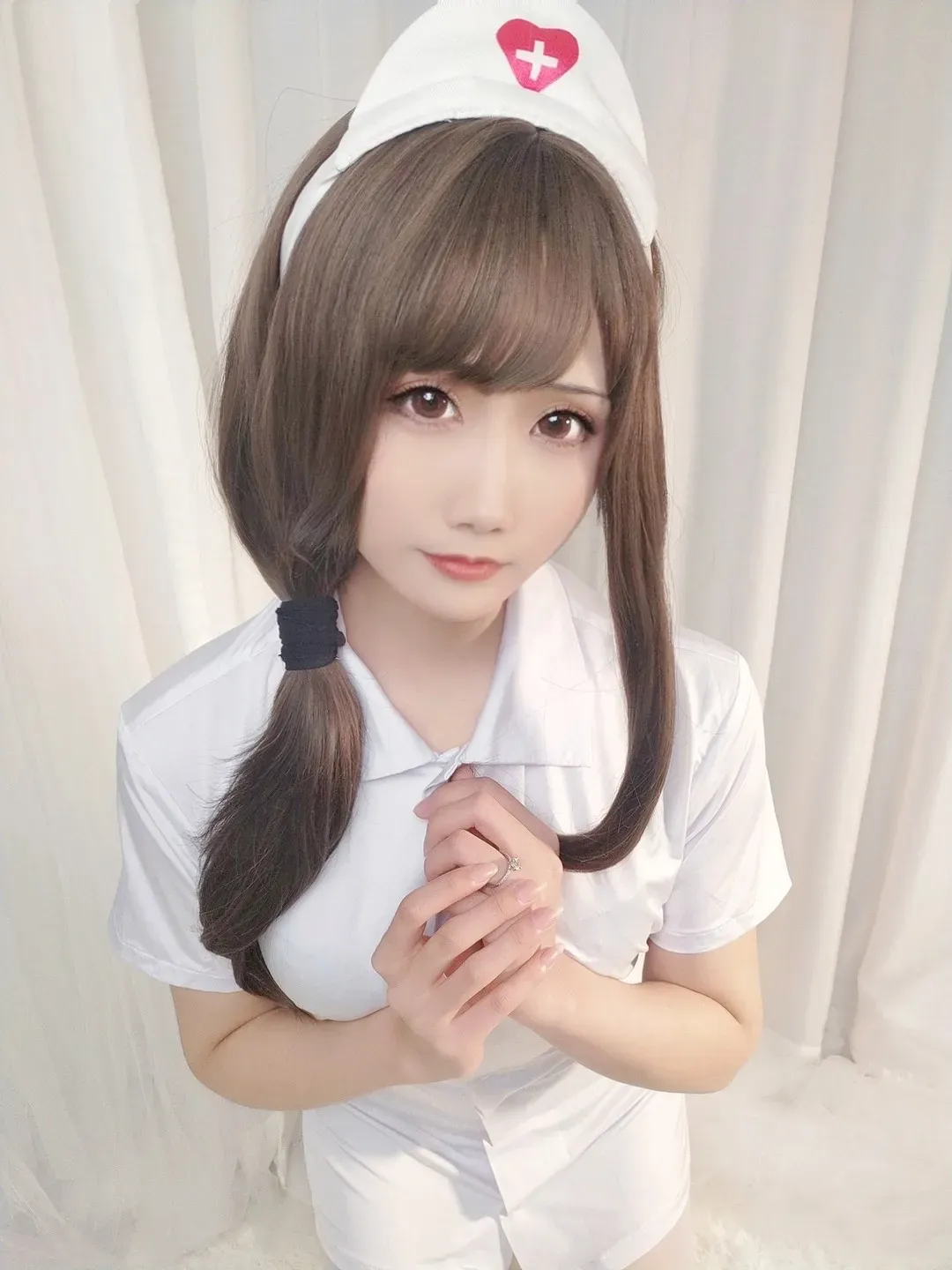 曉美媽穿白色护士服戴护士帽站在浅色帘布前的近景写真