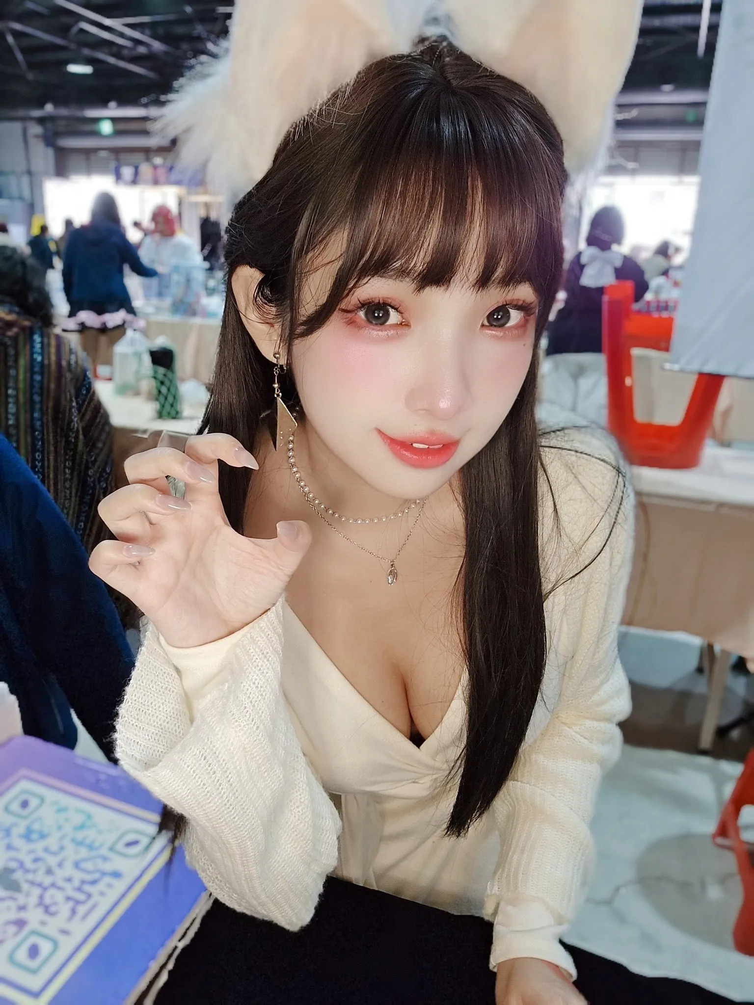 慕慕Momo在活动现场穿白色针织上衣对镜头抬手的照片