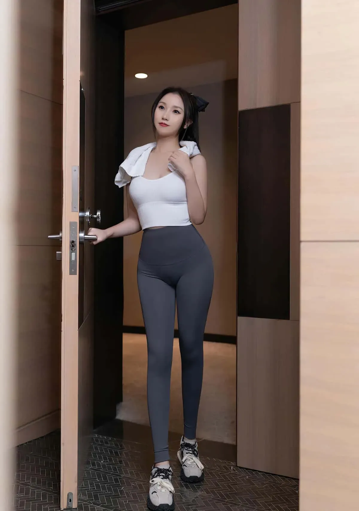 杏子Yada穿白色短上衣和深灰运动裤站在木门之间的写真