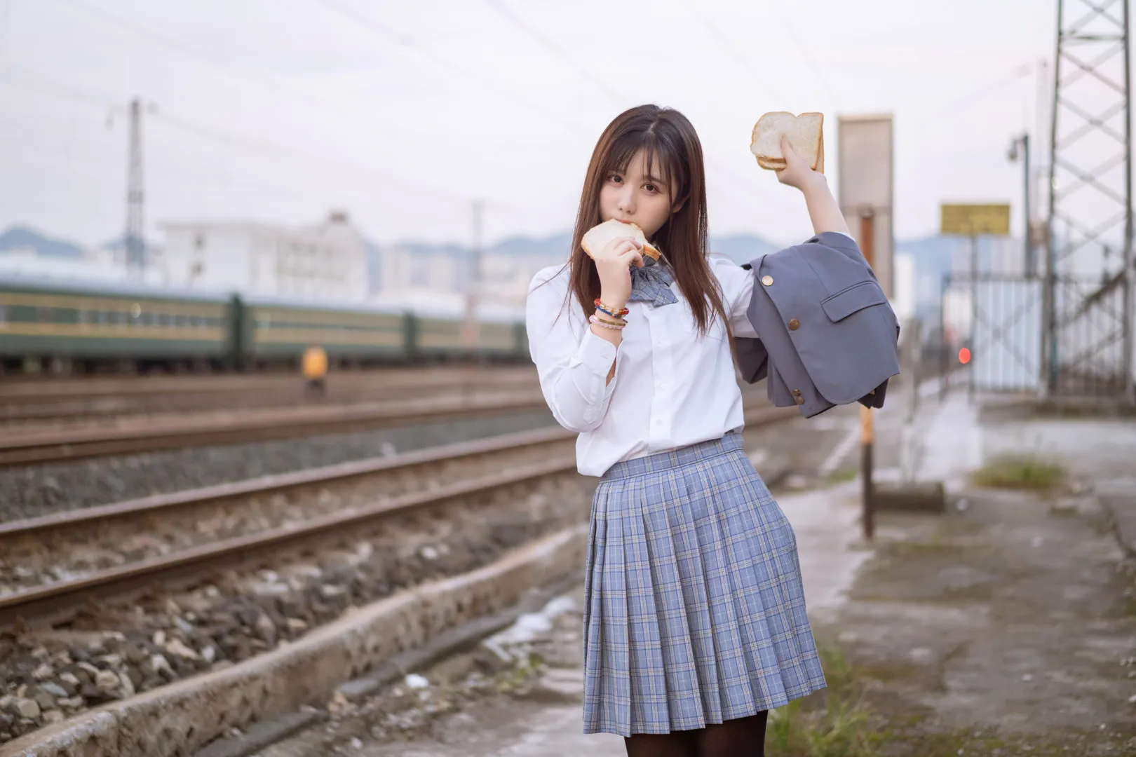 镜酱长发白衬衫格纹裙拿着面包站在铁轨旁的写真