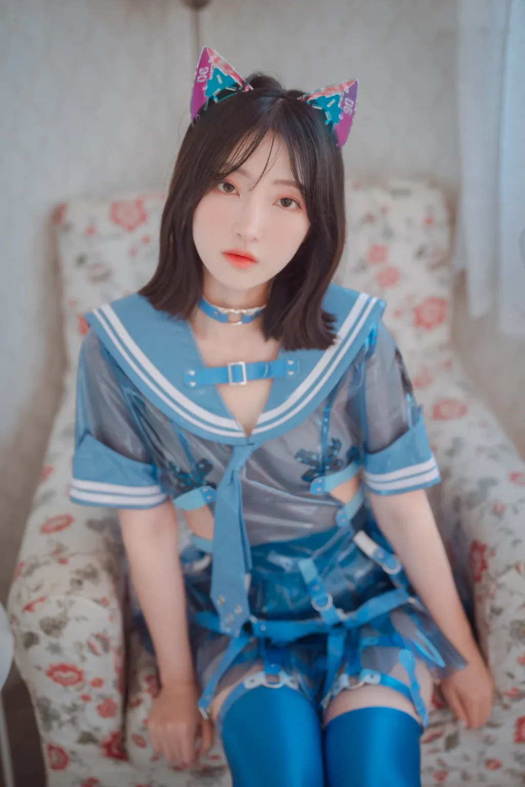 HaNari(하나리)黑色短发，戴蓝色猫耳头饰，穿蓝色制服坐在花纹床面上的cosplay写真