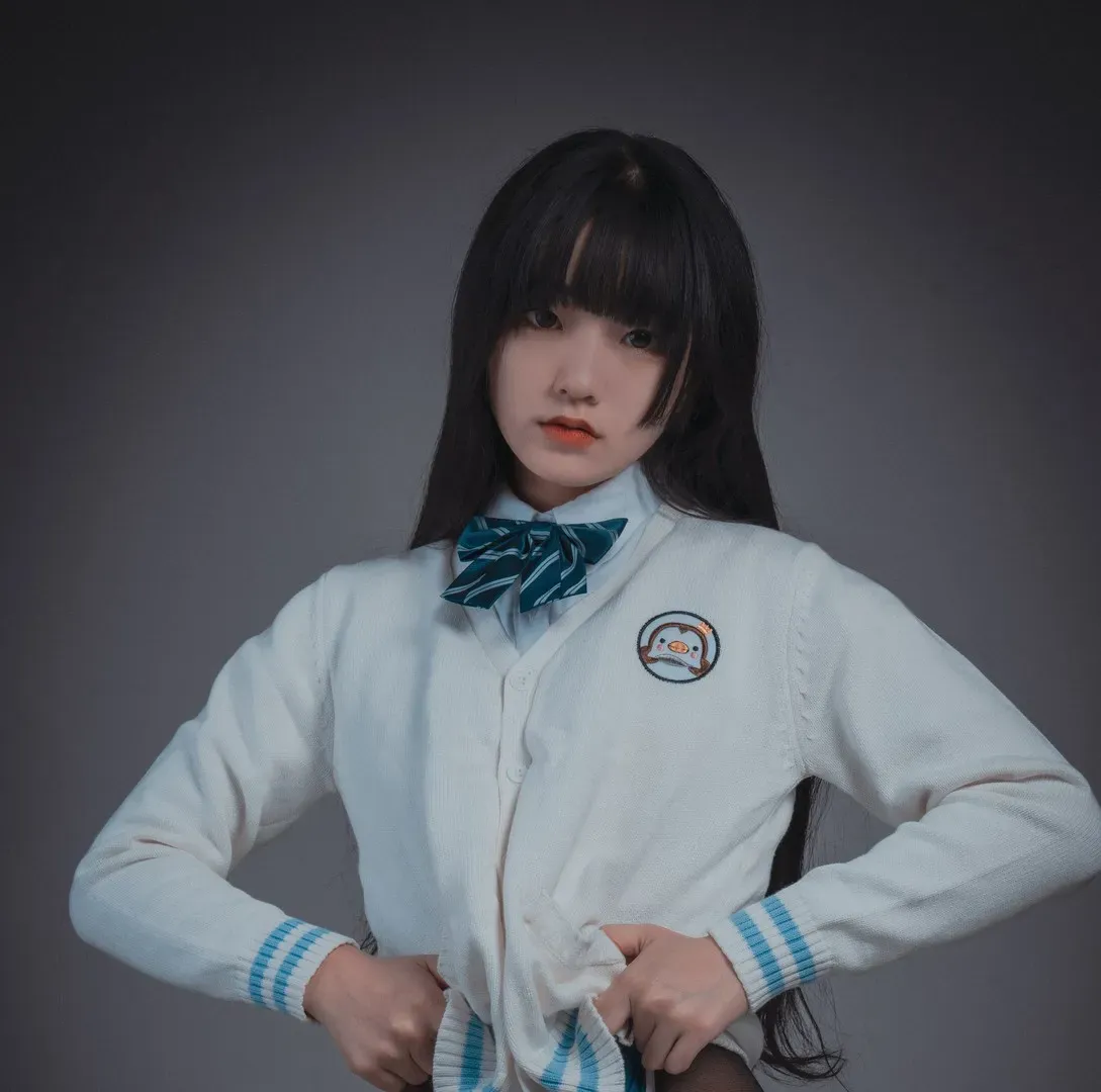 JeongJenny(정제니) 黑色长发穿白色针织开衫和蓝绿色领结站在灰色背景前