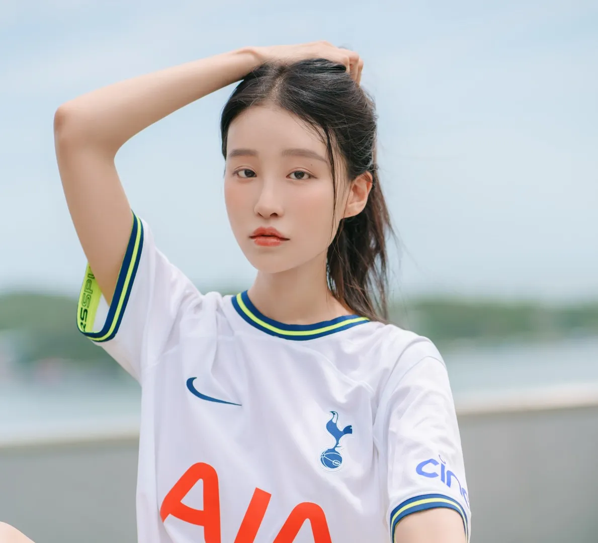 Leesnoww이설 黑发白色球衣手臂抬起站在户外浅蓝背景前的写真