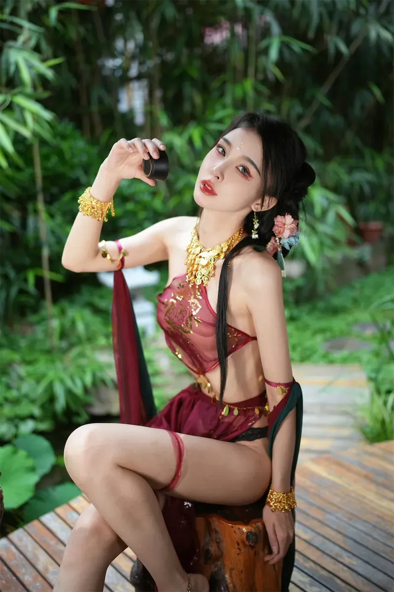 黎允熙baby穿红金服饰坐在竹林绿植前手拿黑色杯子的外景写真