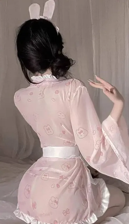 抖音小狼崽粉色服饰搭配兔耳头饰背身写真，室内背景和柔和光线可见