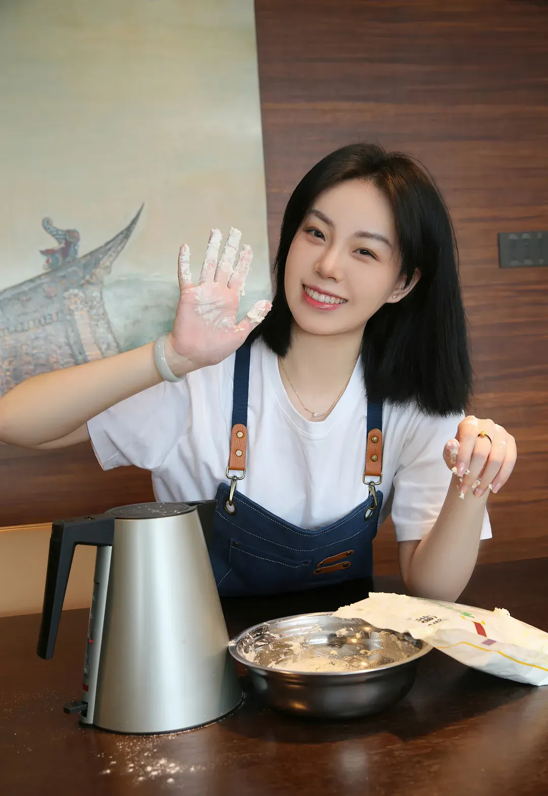 一颗甜蛋黄a短发穿白色T恤和蓝色围裙，手上有面粉，桌上有水壶和金属盆
